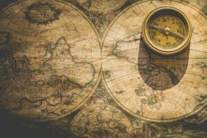 The old-style compass on a parchment map of the world represents each writer's journey to his, her, or their desired writing life.